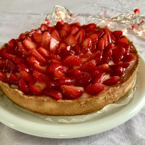 A fresh strawberry tart with a golden biscuit crust, topped with vanilla pastry cream and beautifully layered fresh strawberries.