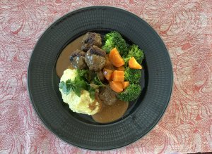 Plate of traditional Finnish meatballs served with creamy mashed potatoes, steamed carrots, and broccoli.
