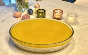 A bright and creamy mango cheesecake topped with a smooth golden mango layer, served in a glass dish with visible layers and a walnut crunch.