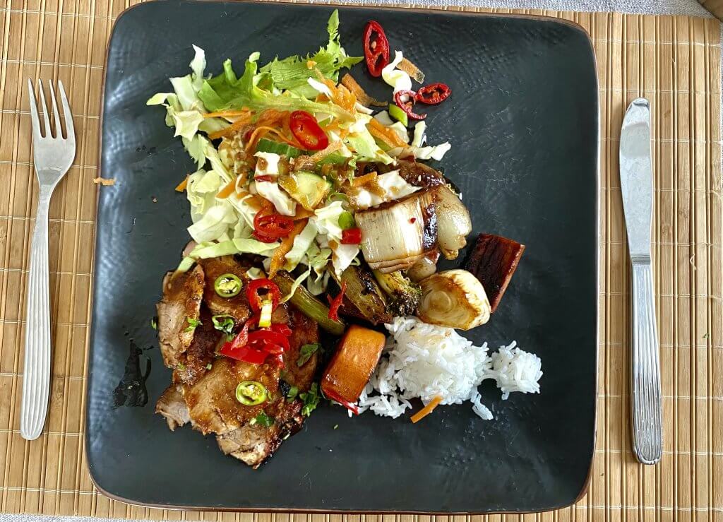 A square plate with juicy Char Siu Pork, steamed jasmine rice, grilled vegetables, and a fresh salad, offering a vibrant, balanced meal.