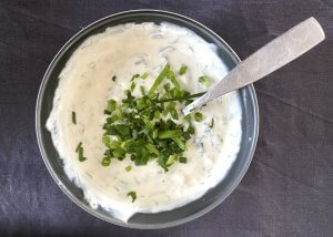Creamy dill and horseradish sauce in a small grey bowl, garnished with fresh herbs