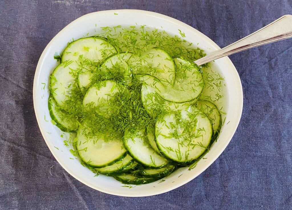 Traditional Finnish pickled cucumbers with dill in a bowl with pickling liquid