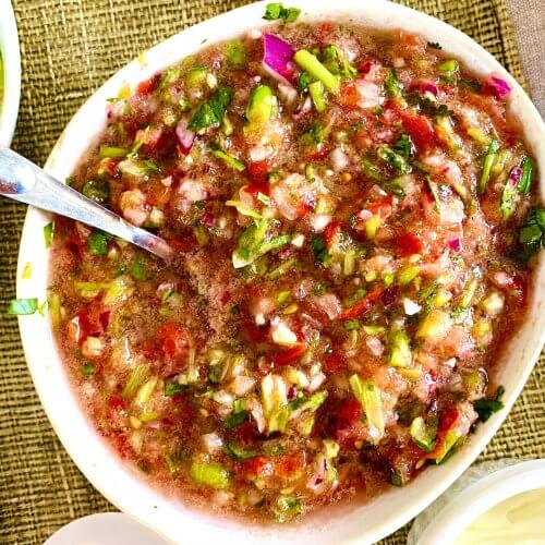 A bowl of freshly made Pico de Gallo featuring diced tomatoes, onions, jalapeños, and chopped cilantro, garnished with lime wedges.