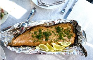 Smoked salmon fillet on a serving plate, garnished with fresh dill and lemon wedges.