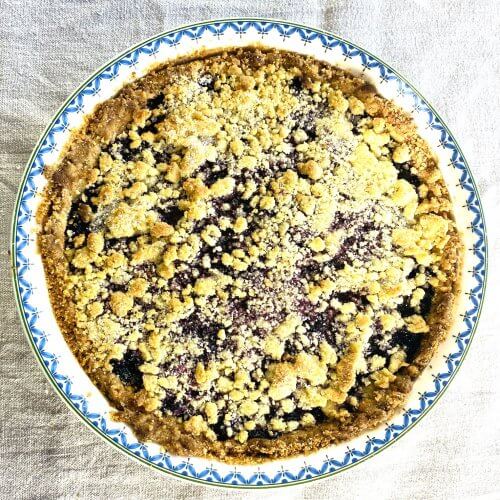 Overhead view of a freshly baked blueberry almond pie in a white decorative pie dish
