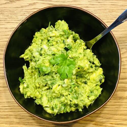 A rustic bowl of freshly made guacamole, topped with chopped cilantro.