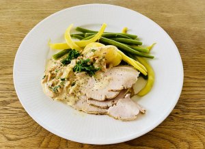 Juicy oven-roasted pork loin marinated with herbs and apple juice, served with chanterelle sauce, green beans, new potatoes, and salad