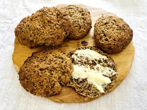 Hearty Finnish Archipelago Bread Rolls on a wooden cutting board, one roll split open with butter on top.