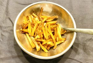 Golden air fryer garlic fries in a metallic bowl, perfectly crisp and lightly browned.