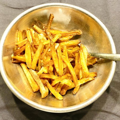 Golden air fryer garlic fries in a metallic bowl, perfectly crisp and lightly browned.