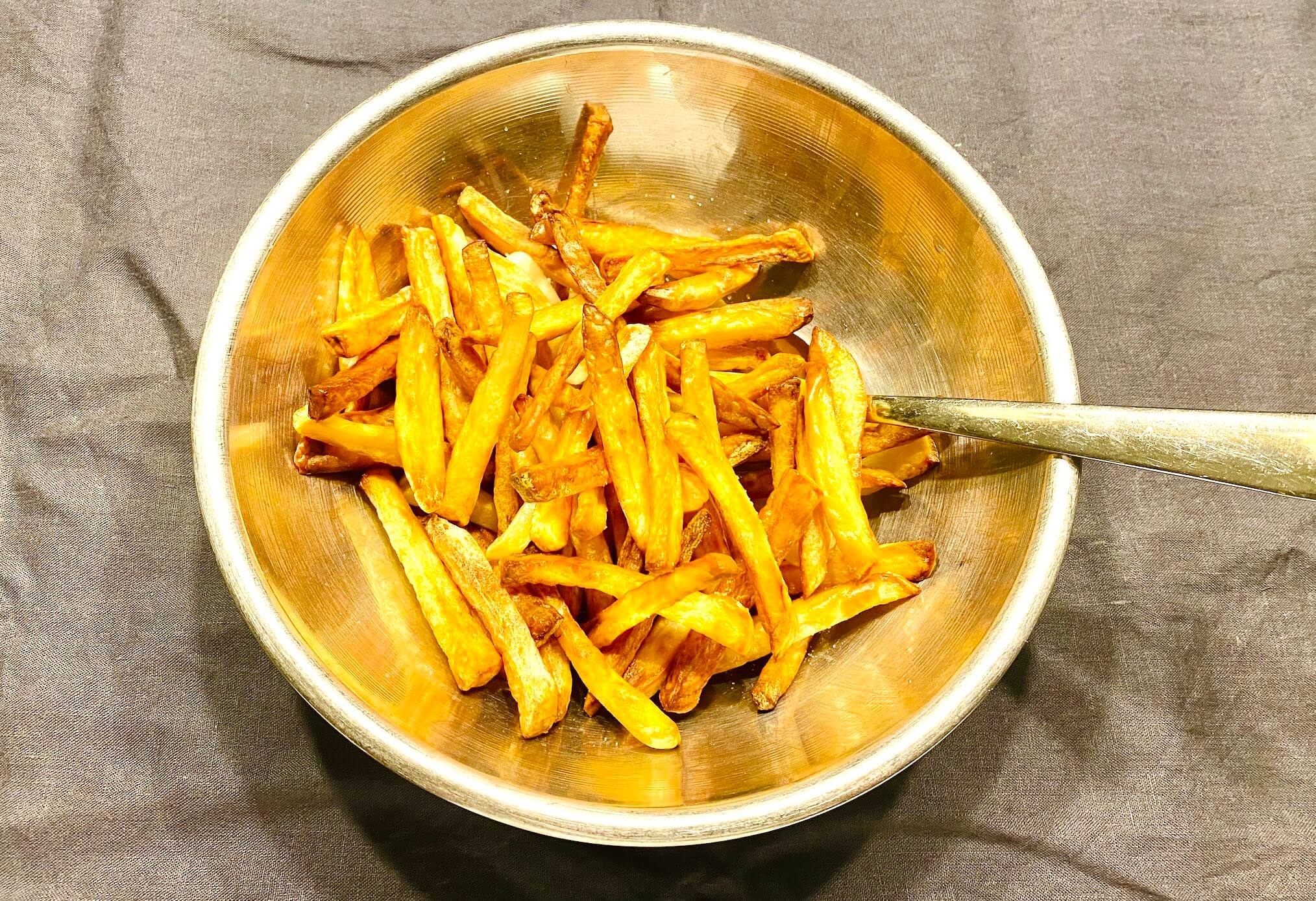 Golden air fryer garlic fries in a metallic bowl, perfectly crisp and lightly browned.