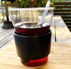 Glass of steaming red glögi, a traditional Finnish spiced drink made with cinnamon, cardamom, and cloves, served warm with raisins and almonds.