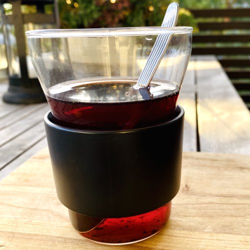 Glass of steaming red glögi, a traditional Finnish spiced drink made with cinnamon, cardamom, and cloves, served warm with raisins and almonds.