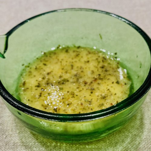 Homemade Provençal mustard salad dressing in a small green glass jug, with a golden, herby texture and a fresh Mediterranean look.