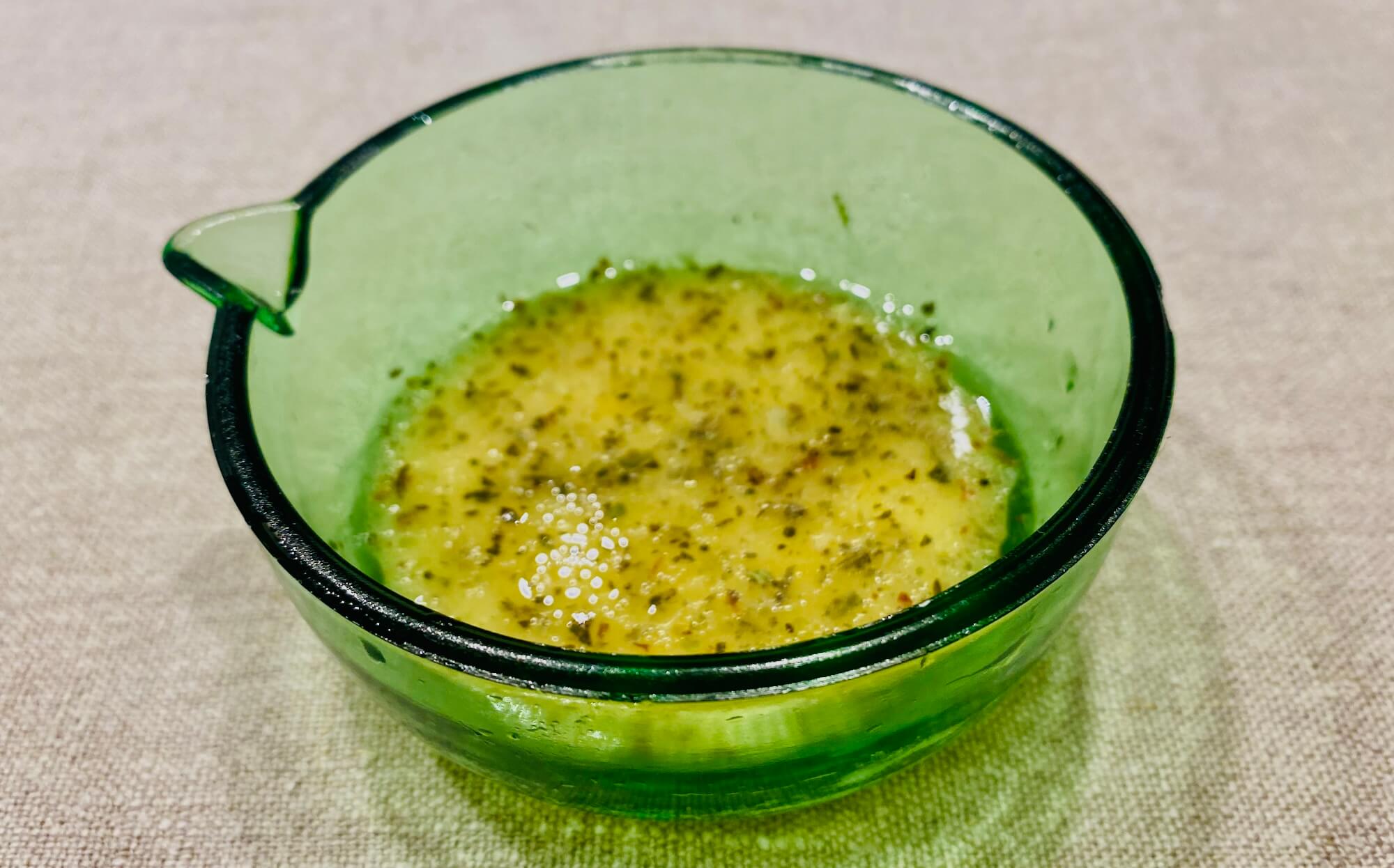 Homemade Provençal mustard salad dressing in a small green glass jug, with a golden, herby texture and a fresh Mediterranean look.