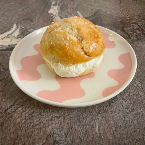 Laskiaispulla, Finnish cream, and almond paste bun on a plate with sugar topping and whipped cream filling.