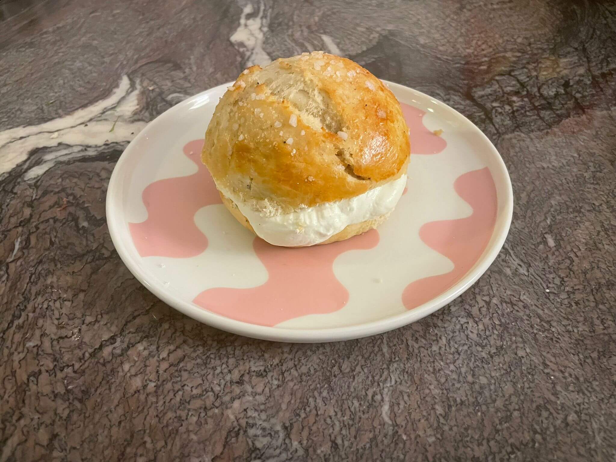 Laskiaispulla, Finnish cream, and almond paste bun on a plate with sugar topping and whipped cream filling.