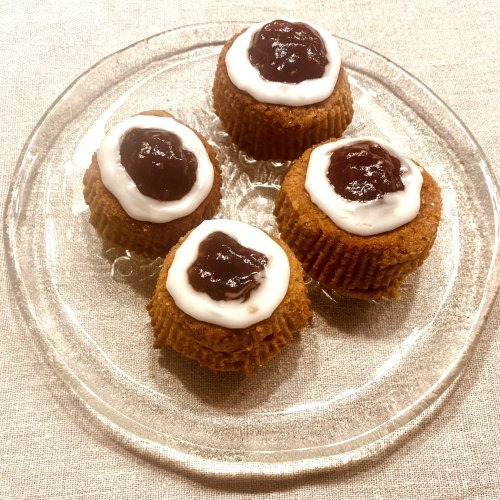 Several rustic Runeberg tortes (Runebergintorttu) on a clear glass plate, topped with raspberry jam and icing