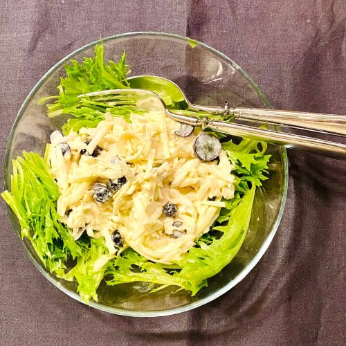 Classic Waldorf salad served in a clear glass bowl with apples, celery, grapes, and walnuts