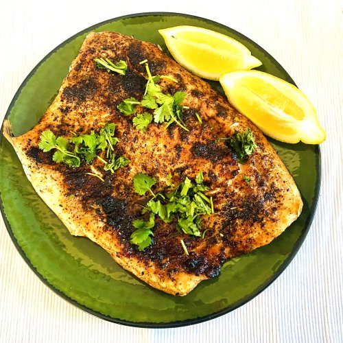Air fryer roasted salmon fillet garnished with fresh cilantro and lemon wedges on a serving plate