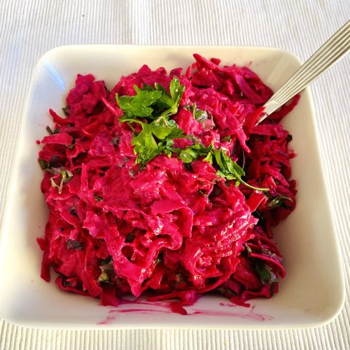 Creamy beet and root celery salad in a serving dish, garnished and ready to serve