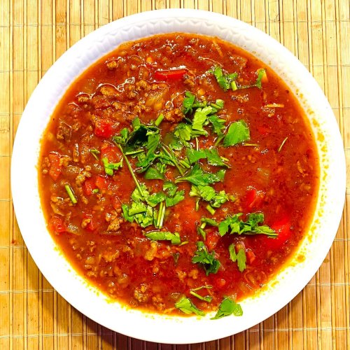 Goulash soup with beef mince served in a bowl, garnished with fresh parsley