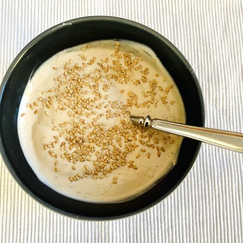 Bowl of creamy sesame yogurt dressing garnished with toasted sesame seeds, ready to serve.