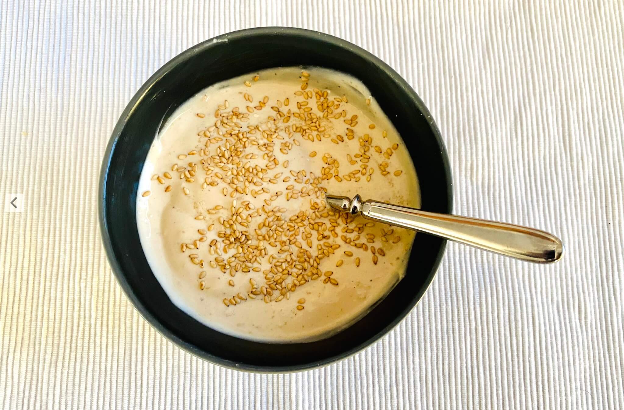 Bowl of creamy sesame yogurt dressing garnished with toasted sesame seeds, ready to serve.