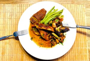 Chicken à l’Orange with port wine sauce served with roasted multi-colored carrots, Hasselback potatoes, and green beans