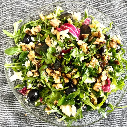 Blue cheese grape salad with mixed greens and caramelized walnuts in a glass bowl