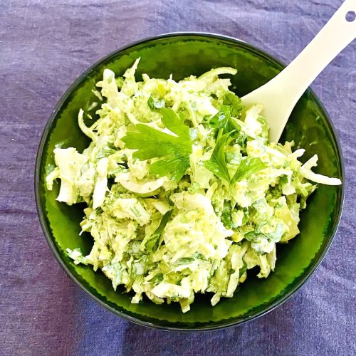 Broccoli slaw with crème fraîche dressing served in a rustic dark green bowl.