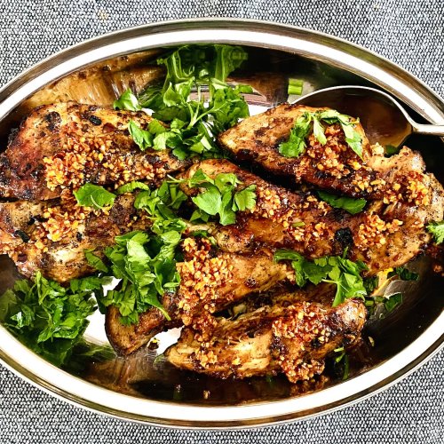 Grilled chicken fillets topped with chili garlic onion sauce on a serving platter