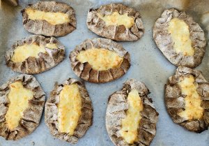 Traditional Finnish Karelian pies baked on a tray with rye crust and rice filling.