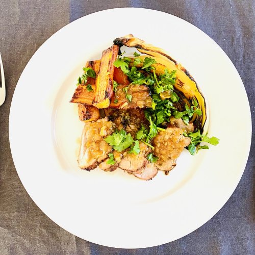 Sliced pork tenderloin served with grilled carrots and cabbage, topped with caramelized onion sauce on a plate.