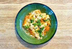 Ricotta spinach tortellini in tomato sauce garnished with fresh herbs, on a plate