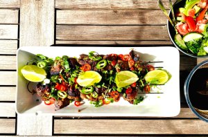 Asian-style pork skewers with chili, cilantro, and lime served with dipping sauce and green salad