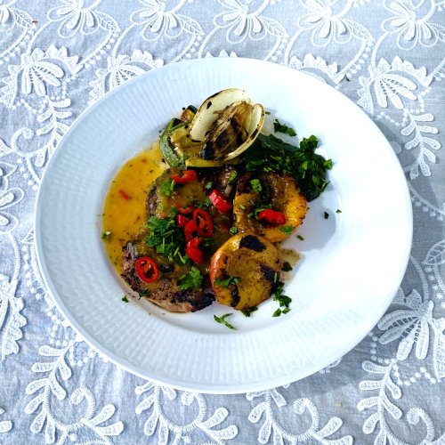 Apricot-glazed pork loin steaks served with grilled vegetables, fresh parsley, and chili slices