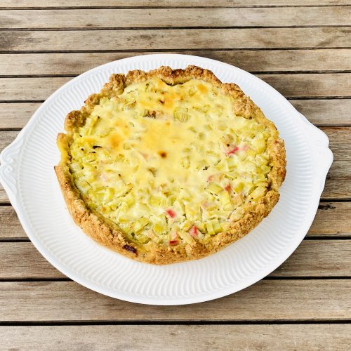 Whole Finnish rhubarb custard pie on a serving plate with a golden crust and creamy rhubarb filling.