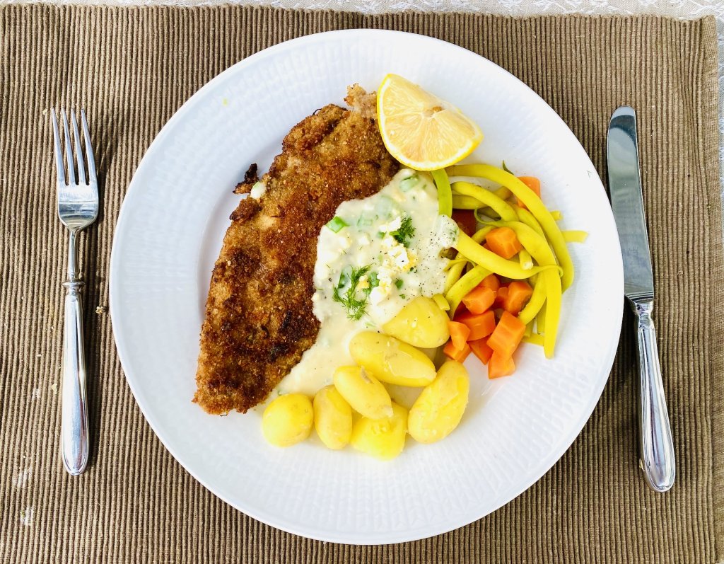 Breaded white fish served with Finnish egg sauce, new potatoes, yellow beans, and carrots