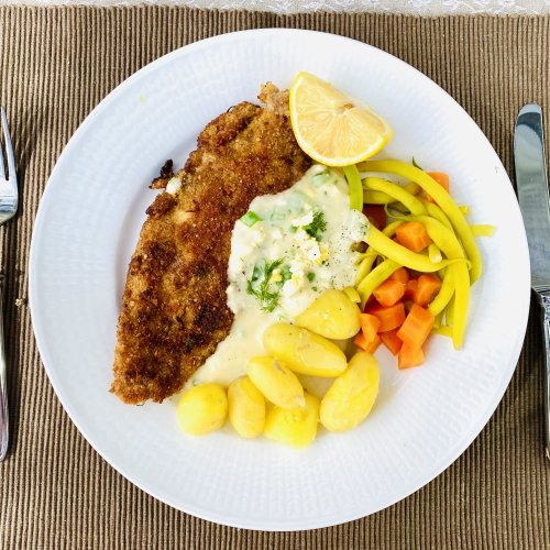 Breaded white fish served with Finnish egg sauce, new potatoes, yellow beans, and carrots