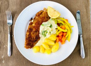 Breaded white fish served with Finnish egg sauce, new potatoes, yellow beans, and carrots