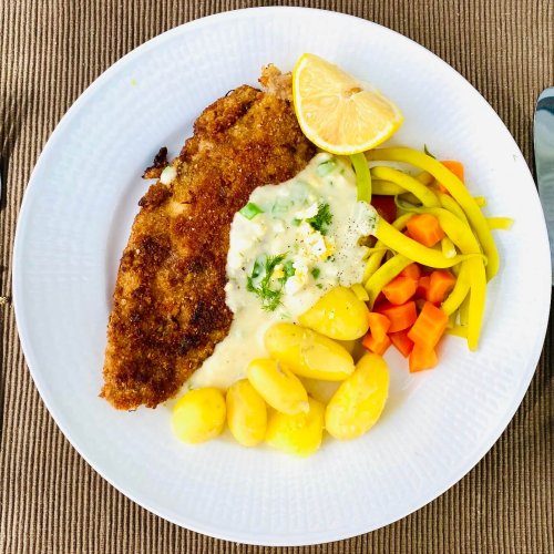 Breaded white fish served with Finnish egg sauce, new potatoes, yellow beans, and carrots