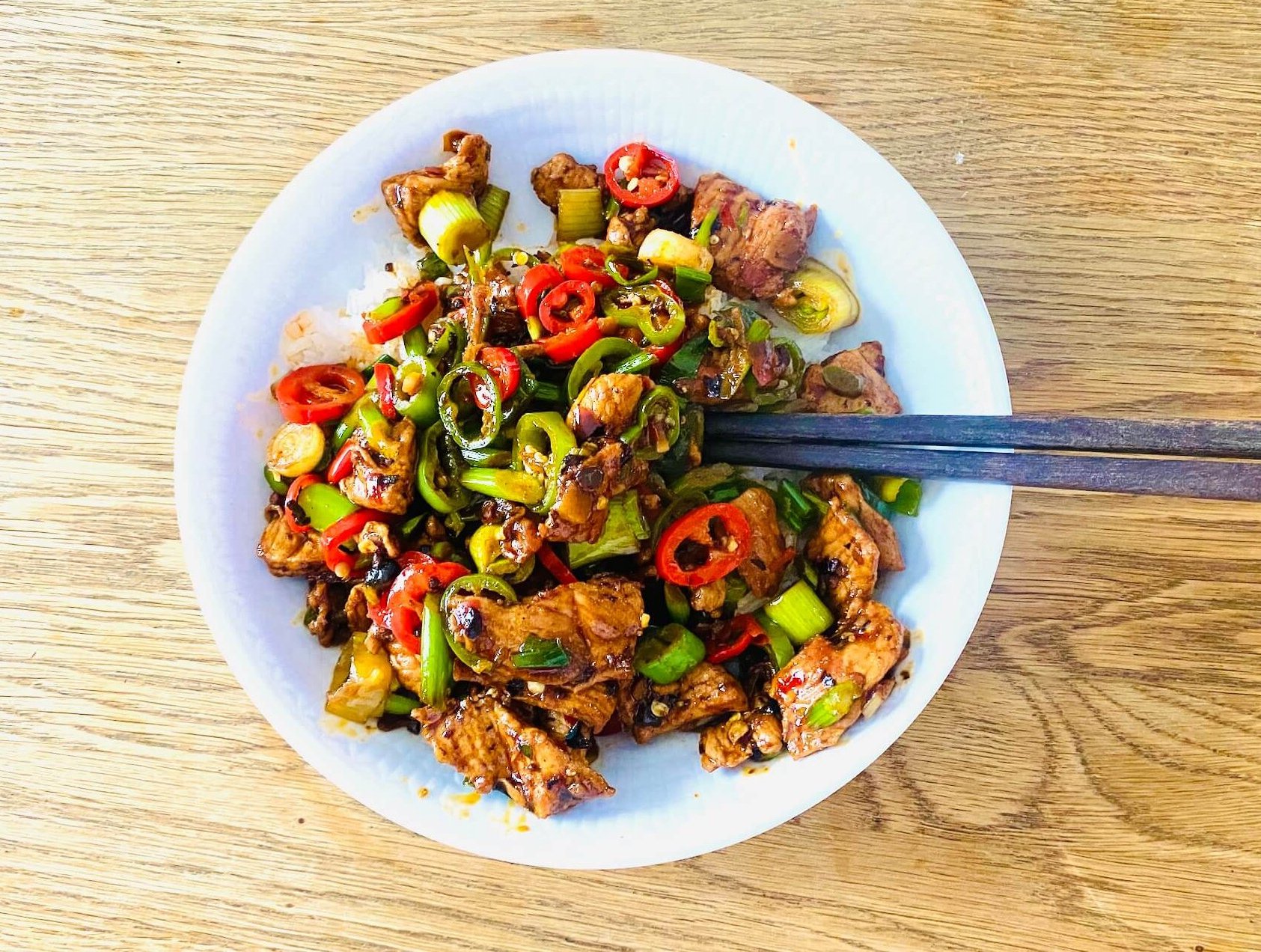 Sichuan chili pork served with steamed jasmine rice and chopsticks