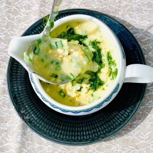 Creamy Finnish egg sauce in a gravy boat, garnished with fresh dill and chives, with the sauce pouring from a gravy ladle