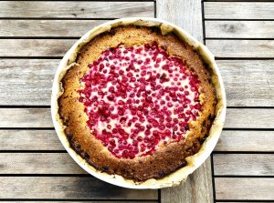 Red Currant Sour Cream Pie in a pie dish, topped with fresh red currants and baked until golden.