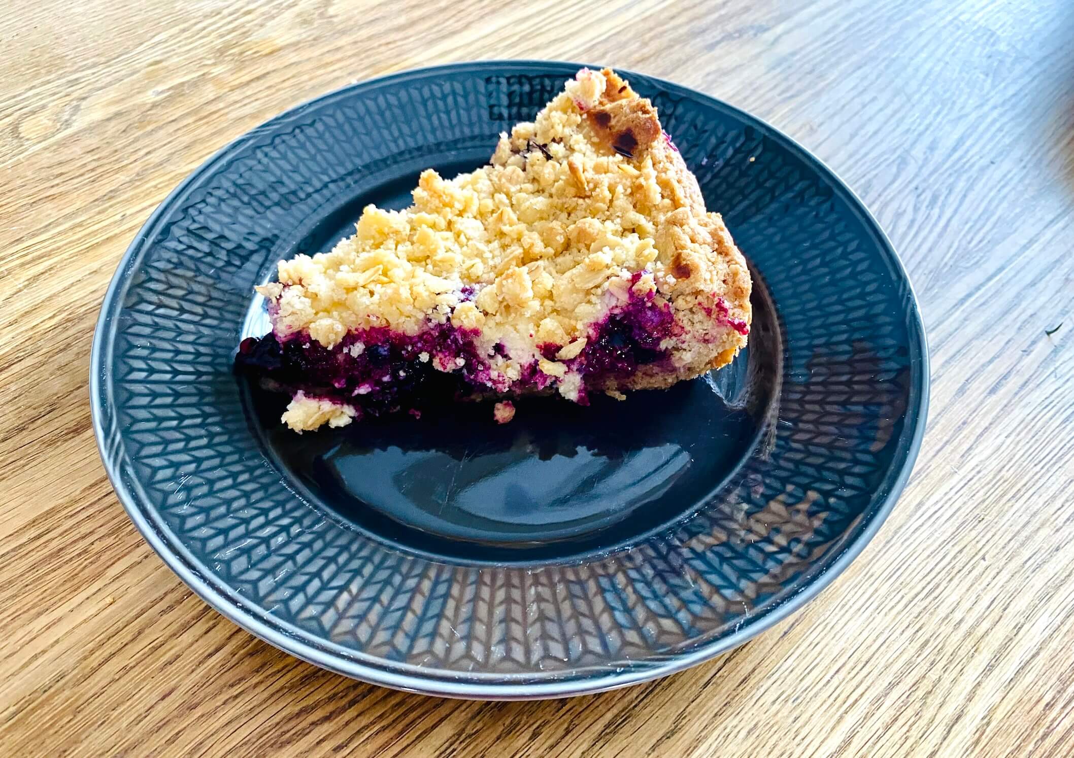 Slice of blueberry crumble pie with lemon filling showing the juicy blueberry filling and golden oat crumble topping