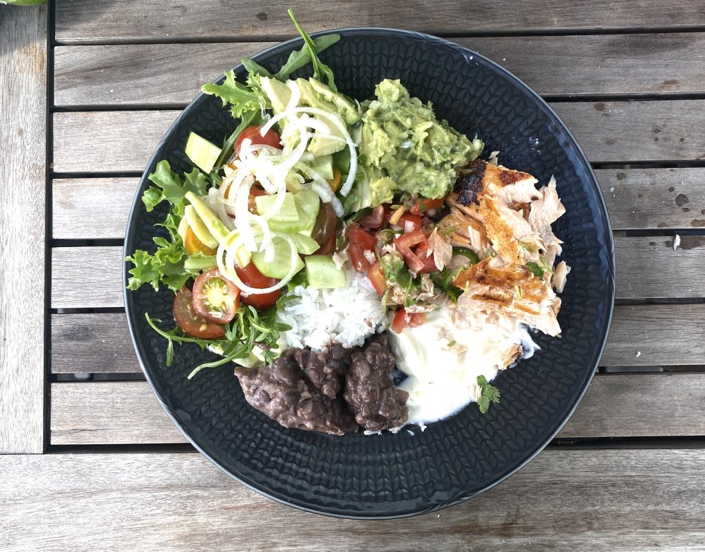 Grilled jalapeño lime salmon served with rice, salad, guacamole, pico de gallo and black beans