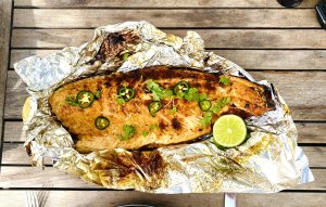 Grilled salmon fillet with jalapeño and lime, garnished with fresh herbs