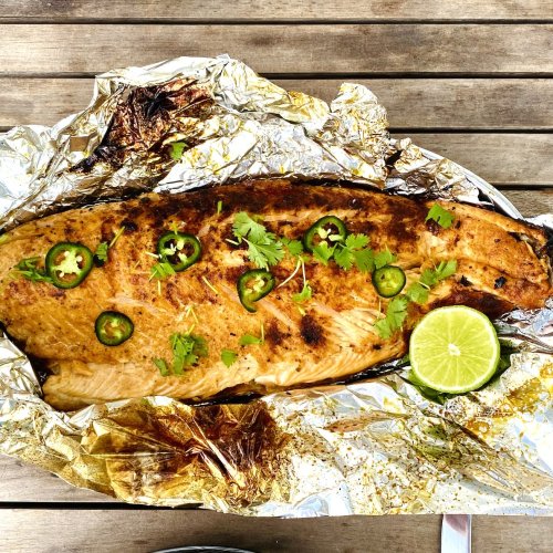Grilled salmon fillet with jalapeño and lime, garnished with fresh herbs