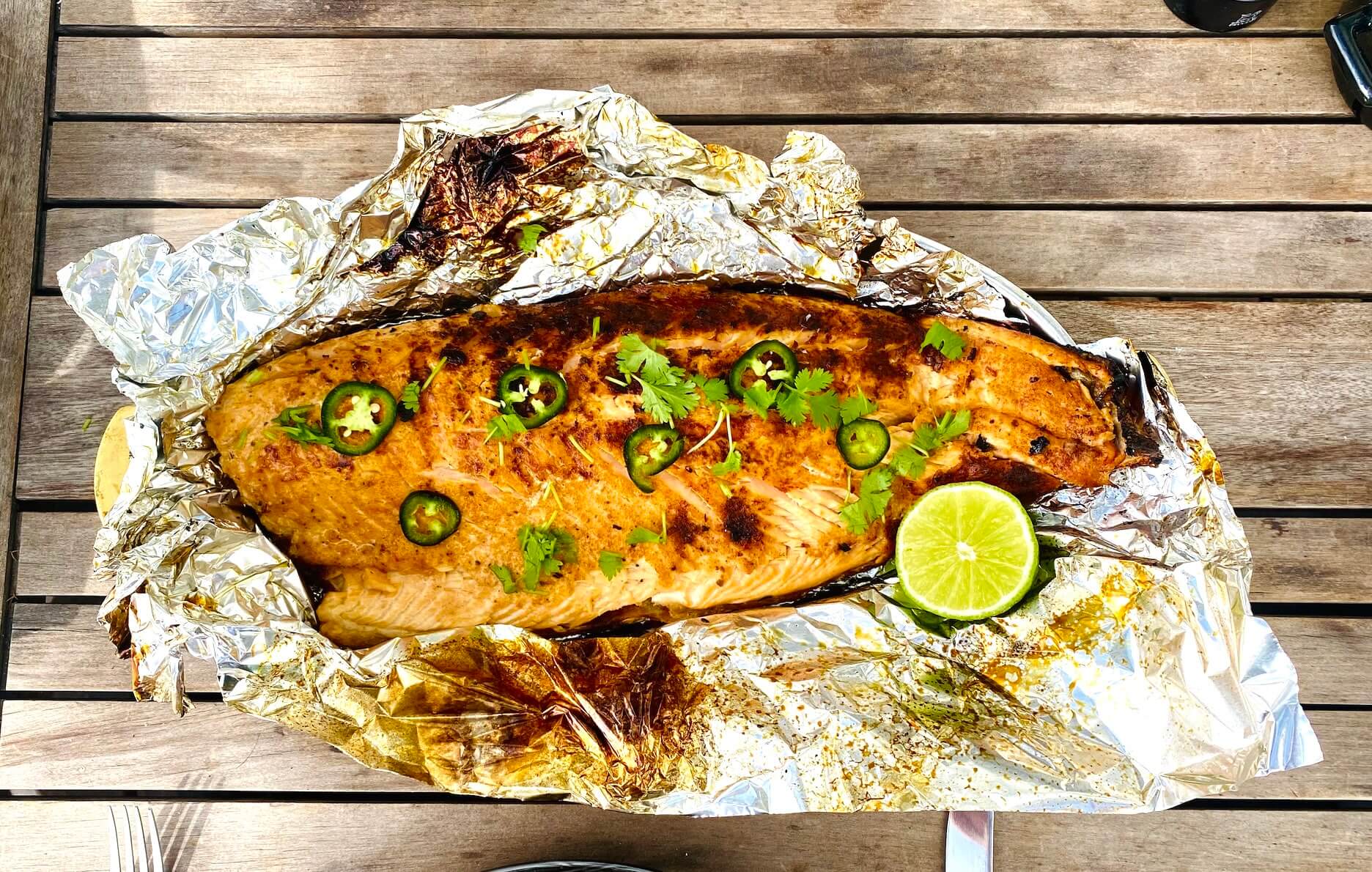 Grilled salmon fillet with jalapeño and lime, garnished with fresh herbs